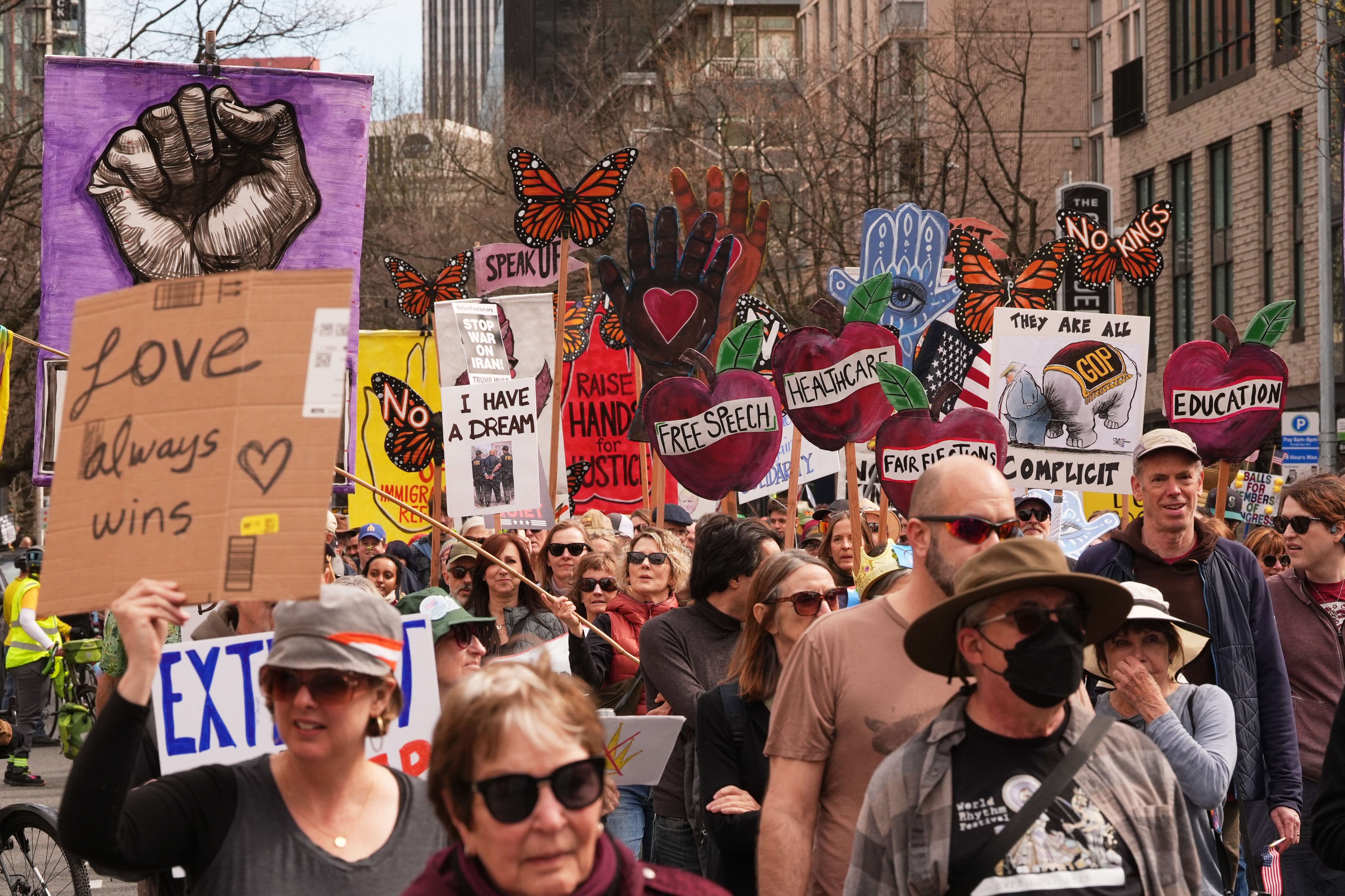 Protesters march in a Seattle Street, carrying signs that read