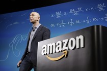 Jeff Bezos standing next to a podium that says "Amazon"