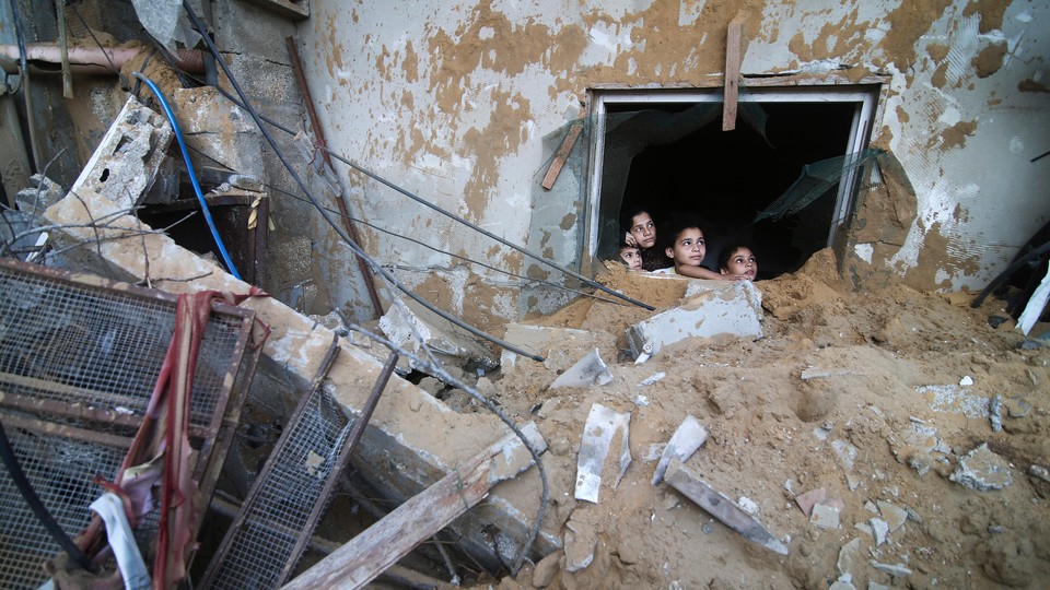 Palestinian children look at the building of the Zanon family, destroyed in Israeli airstrikes in Rafah, Gaza Strip, Saturday, Oct. 14, 2023.