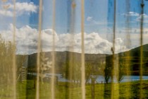 a view of mountains and grass through a curtain