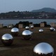 A memorial made of large metallic silver balls overlooking a bay and seaside town