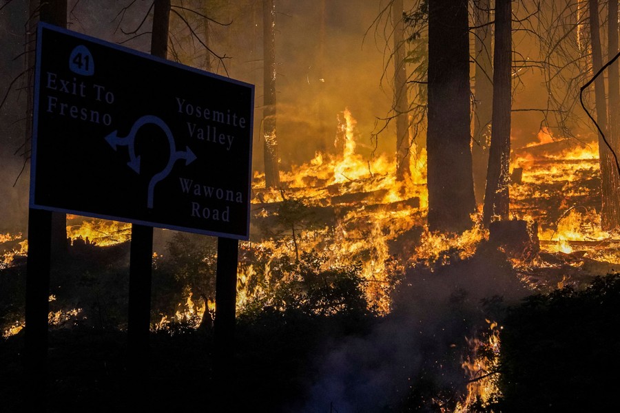 A burning forest, beside a highway sign