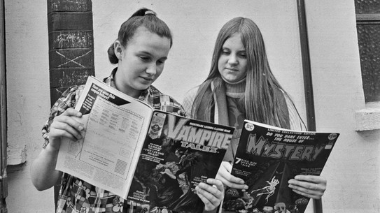 Two teenage girls reading comic books