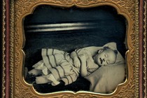 A framed black-and-white image of a deceased infant