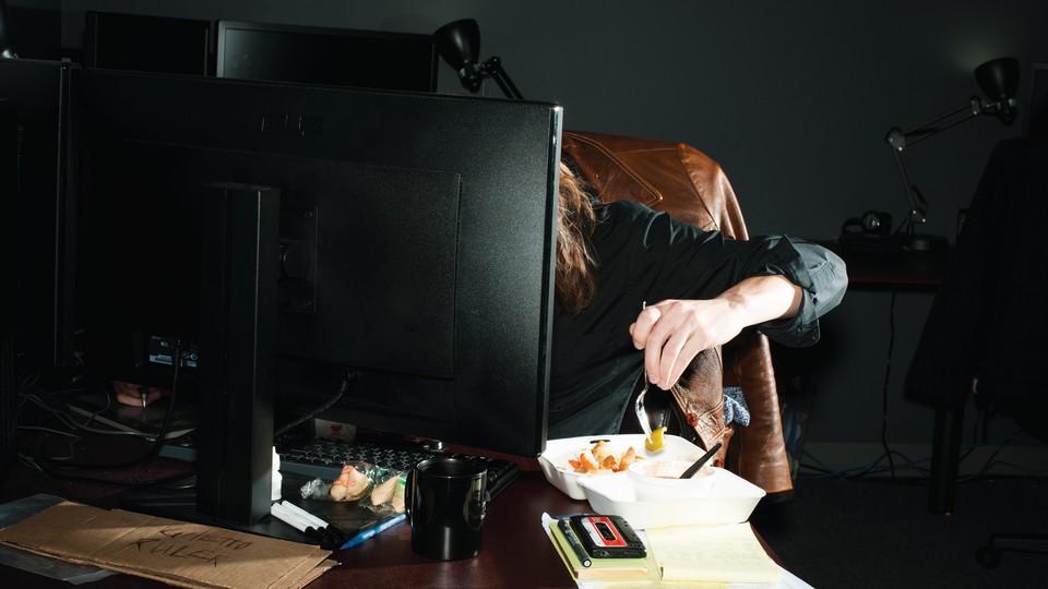 A woman eating in front of a computer