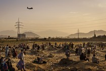 A military transport plane launches while stranded Afghans who cannot get into the airport to evacuate watch and wonder, in Kabul, Afghanistan