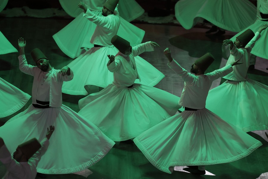 Whirling dervishes perform under green lighting.