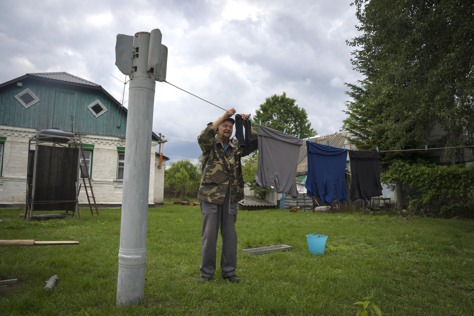 A person hangs laundry on a line attached to a pole fashioned from a fragment of a Russian rocket.
