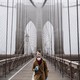 A woman wearing a mask and carrying a coffee cup on a bridge