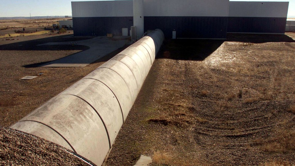 Concrete and steel tubes next to a plain building in a brown landscape