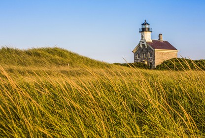 A granite lighthouse surrounded by grass, on Rhode Island's Block Island