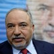 Avigdor Lieberman stands in front of a painted image of himself.