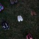 Pairs of shoes arranged in rows on grass