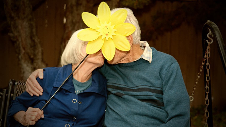 An older couple with a flower covering their faces