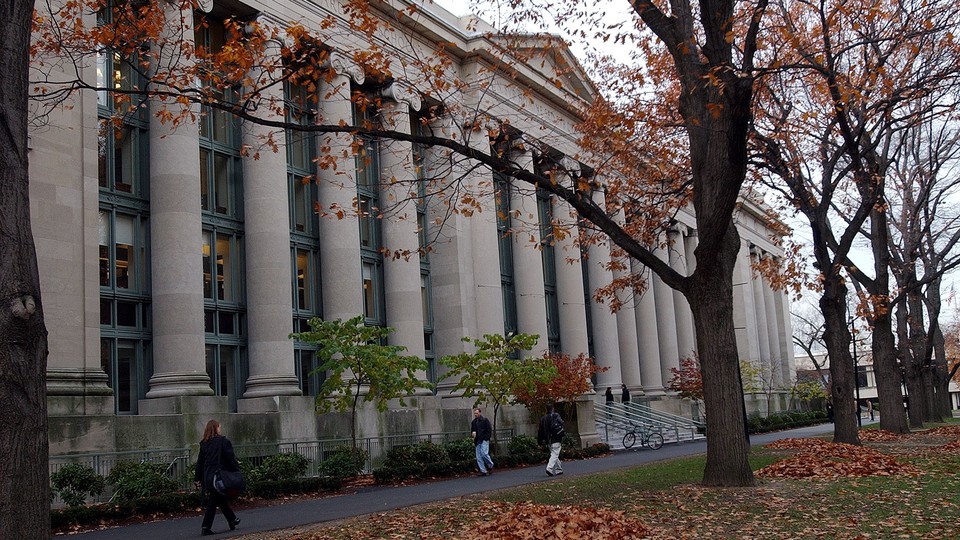 Students walk in front of a large, judicial-looking building on Harvard's Law School campus in the fall.