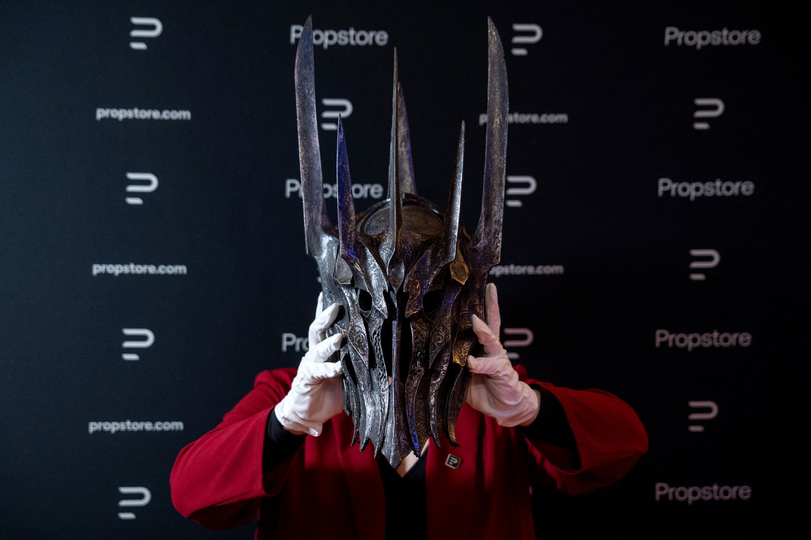 A person holds up a movie prop helmet from the Lord of the Rings movie trilogy.