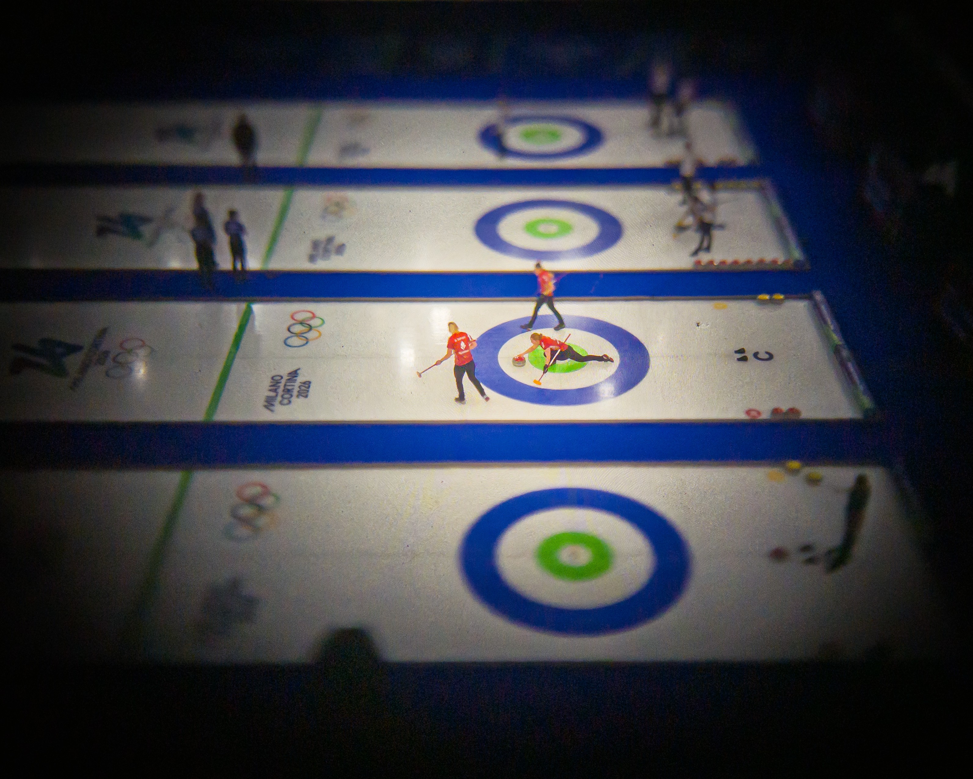 An elevated view of a curling competition, seen through an older camera lens with a dark vignette effect.