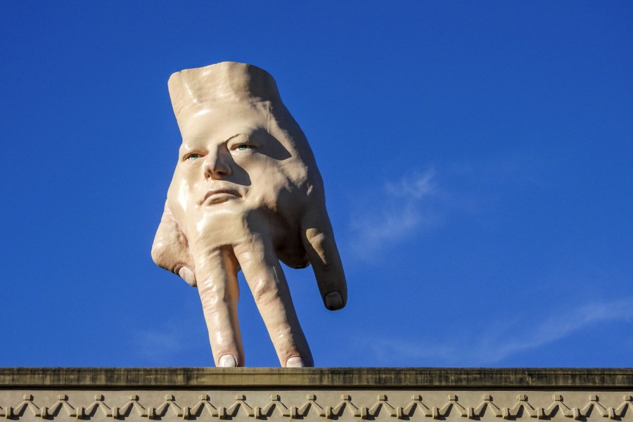 A 16-foot-tall sculpture shaped like a human hand with a face stands on a rooftop.