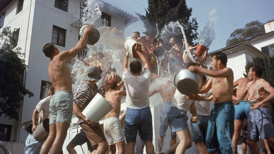 Fraternity brothers throw water at each other using buckets.
