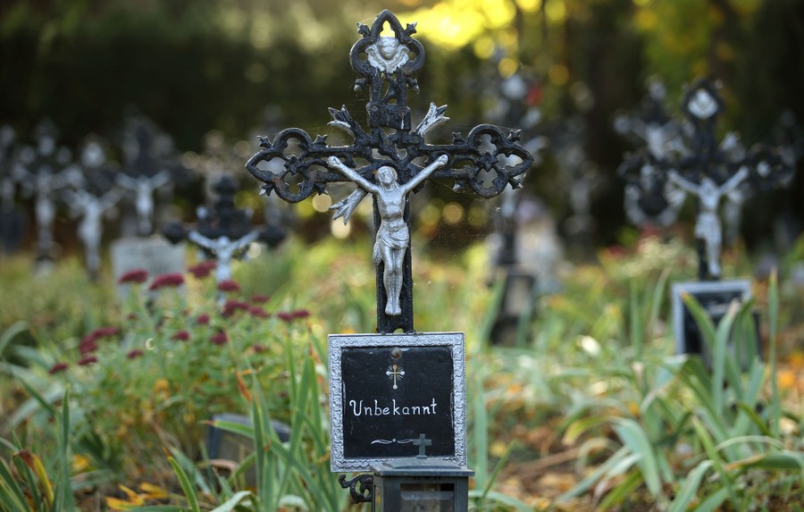 About a dozen small grave markers stand in a cemetery, the one at center reads "Unbekannt"—"Unknown," in English.