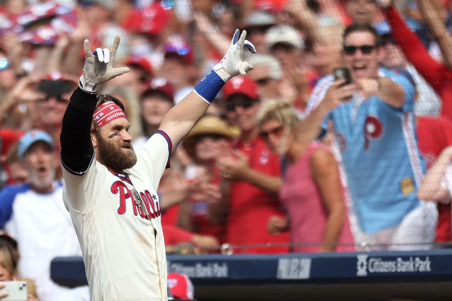 A baseball player raises his arms to celebrate as fans cheer in the background.