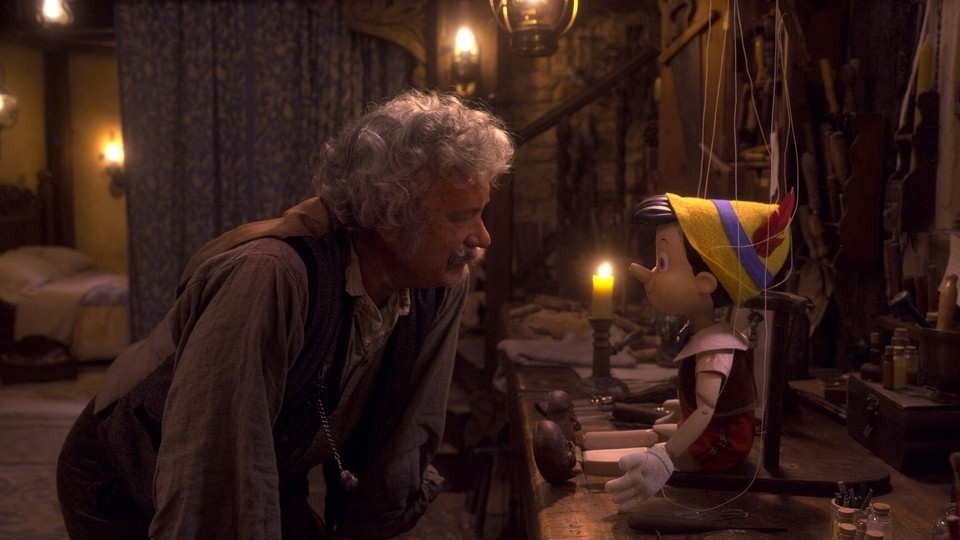 Tom Hanks as Geppetto in his workshop looking at a Pinocchio doll