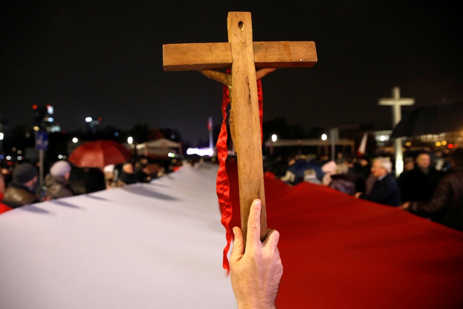 A person holds up a wooden cross during a pro-government march in Poland.