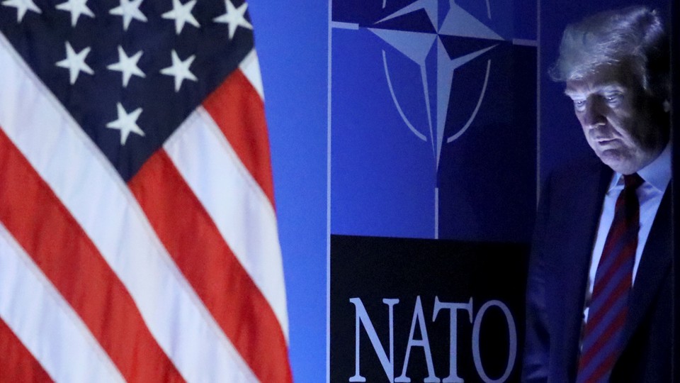 Donald Trump walks onto the stage to deliver a press conference at the NATO summit in Brussels