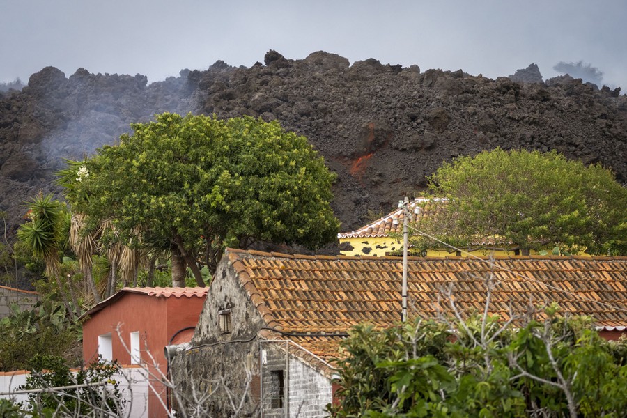 A large wall of rocky lava approaches several houses.