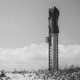 A pair of onlookers gaze at SpaceX's Starship system, which stands upright on its launchpad on the coast of South Texas.
