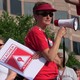 Angie Scioli holds a megaphone and a poster that reads "teacher demonstration in progress"