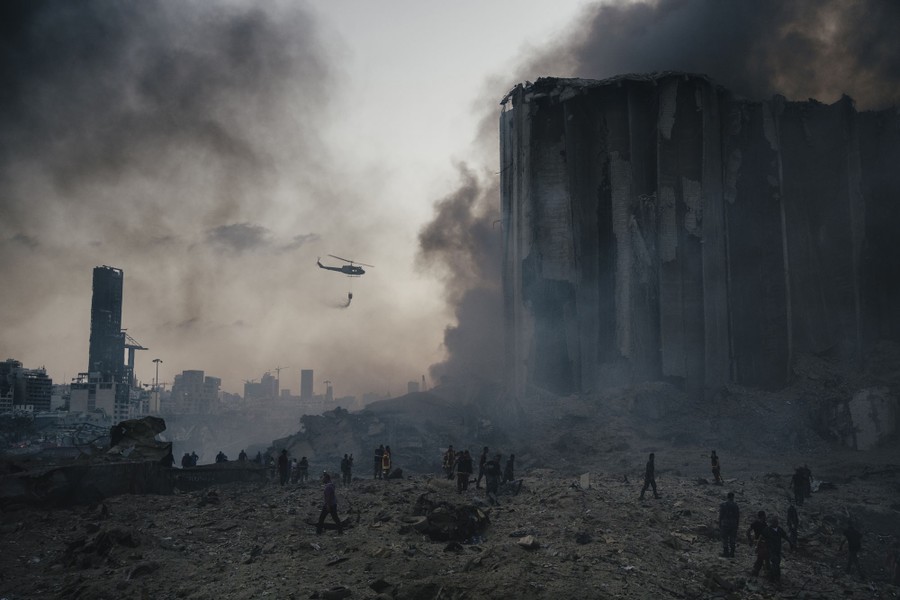 A helicopter flies over the wreckage left by a massive explosion in Beirut.