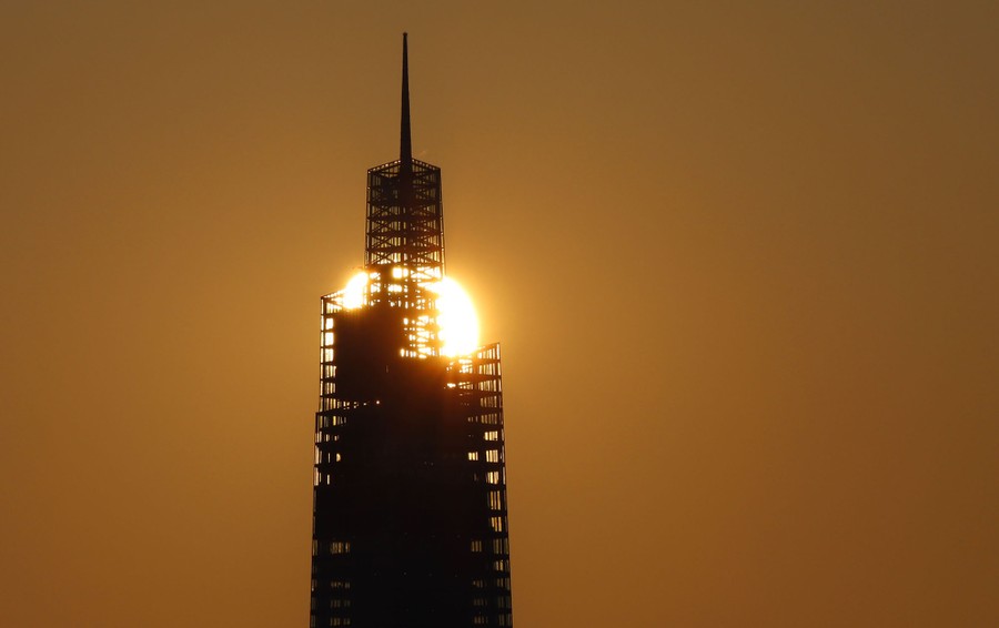 The sun rises behind a skyscraper.