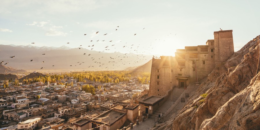 A wide view of a centuries-old fortress perched on a hillside above a city in India.