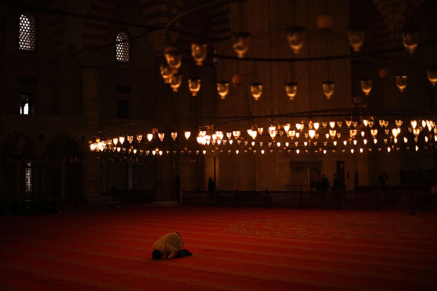 Ένα άτομο γονατίζει σε προσευχή μέσα σε ένα ως επί το πλείστον άδειο τζαμί.