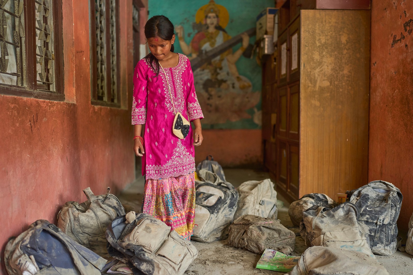 A student searches for her school bag in a pile of backpacks extracted from the mud after a flood.