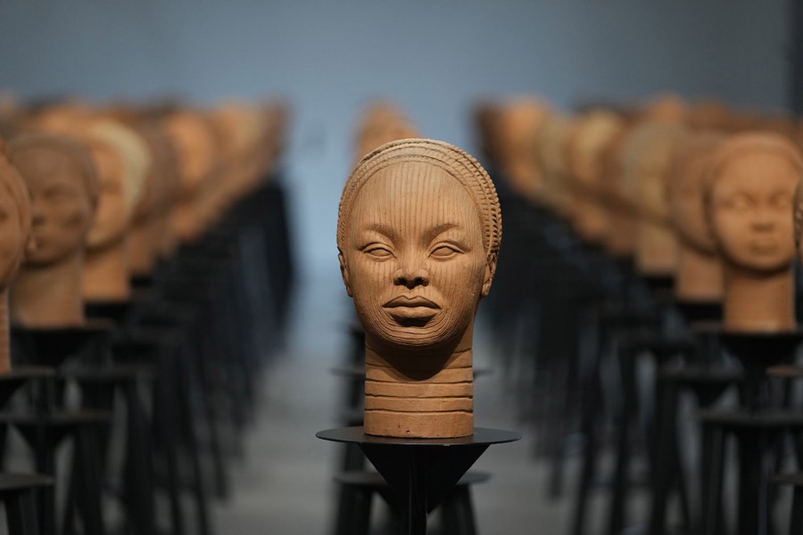 Dozens of terracotta busts sit in rows in a display.