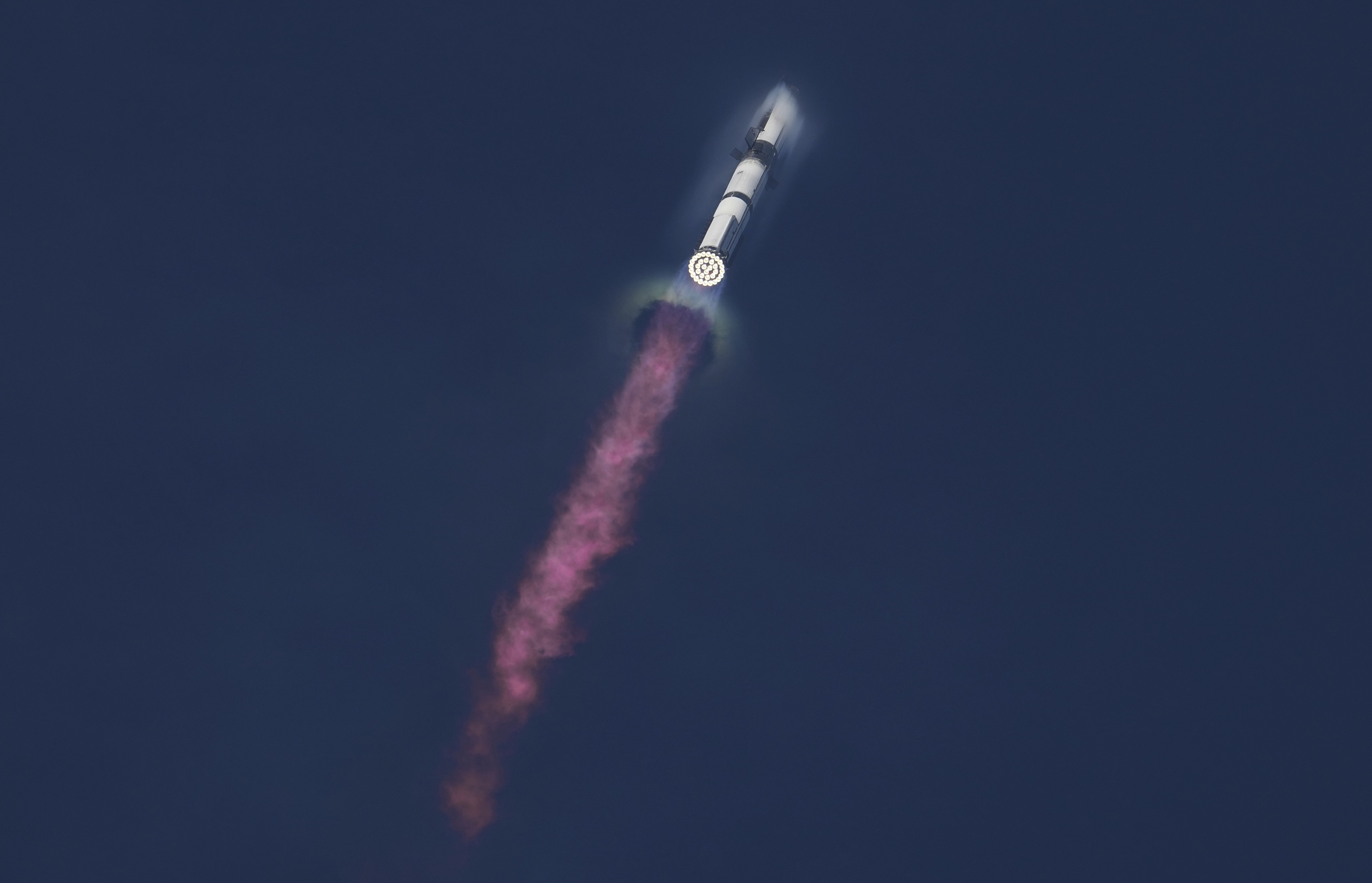 A large rocket rises through the air after a launch, leaving a long trail of exhaust.