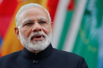 India's Prime Minister Narendra Modi looking at the camera in front of a row of flags.