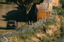 Texas State Troopers talk with migrants behind razor wire along the Rio Grande River in Eagle Pass, Texas, US, on July 13, 2023.