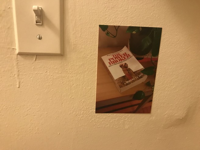 A photo of a copy of The Power Broker, taped to a wall, next to a light switch.