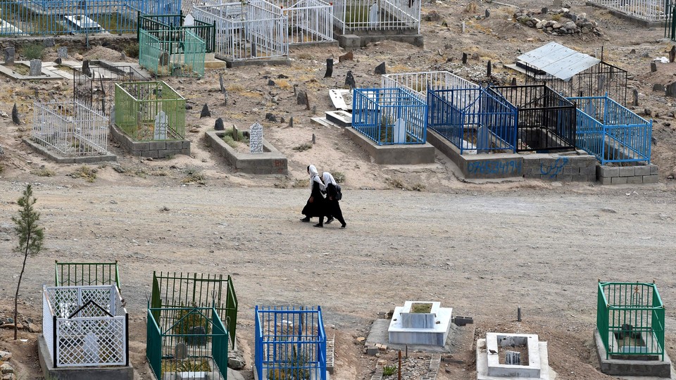 Afghan schoolgirls walking through a cemetery.