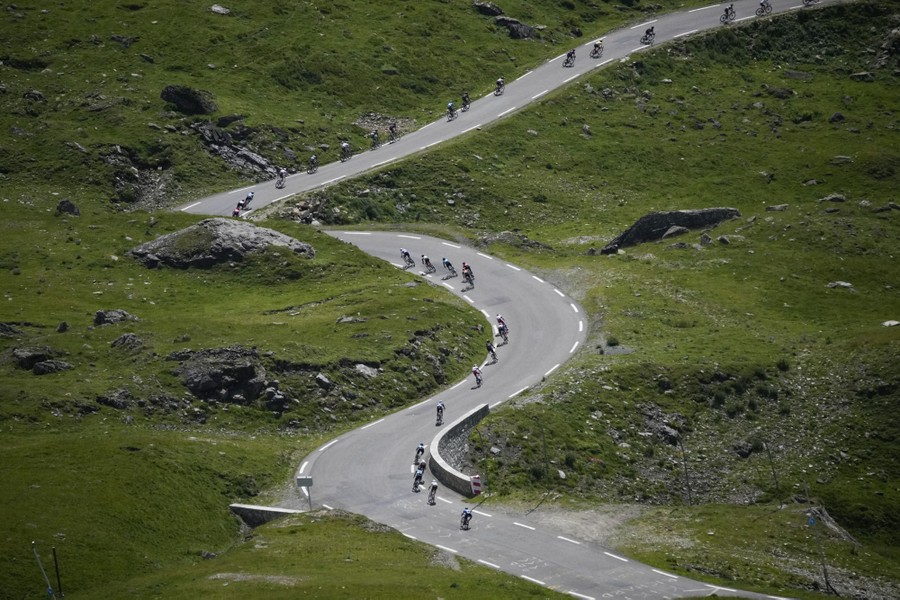 Cyclists ride on a twisting mountain road.