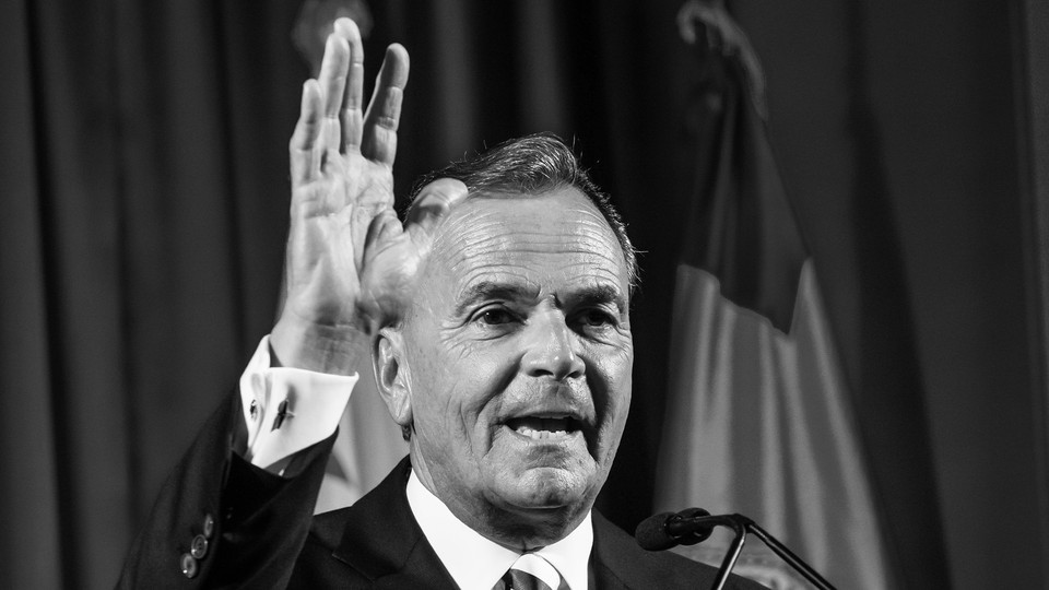 A black-and-white photograph of Rick Caruso at a podium