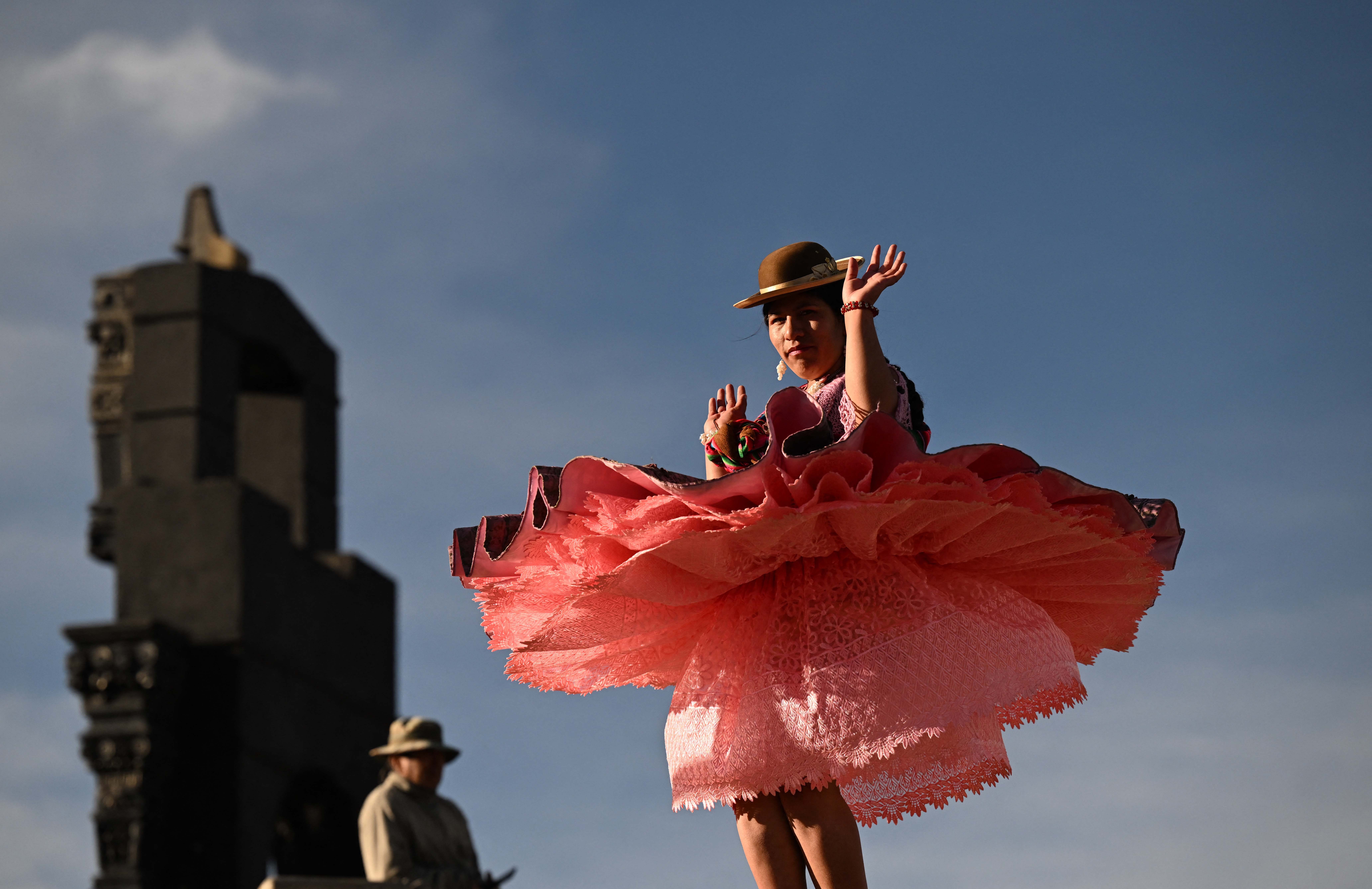 A woman wearing traditional Bolivian clothing dances.