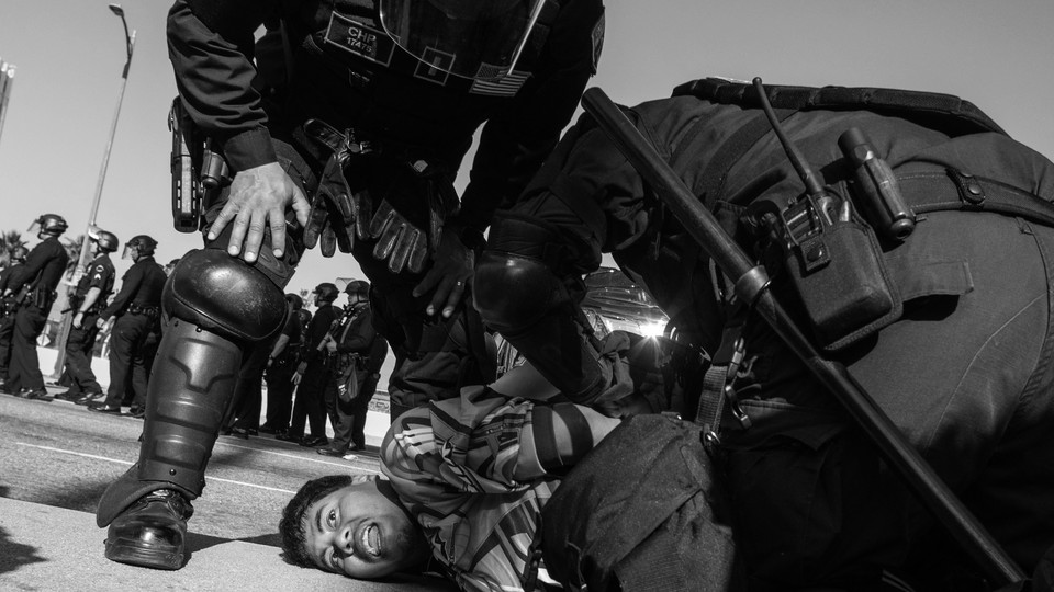Black-and-white image of California Highway Patrol officers holding to the ground and arresting a demonstrator at the L.A. protests.