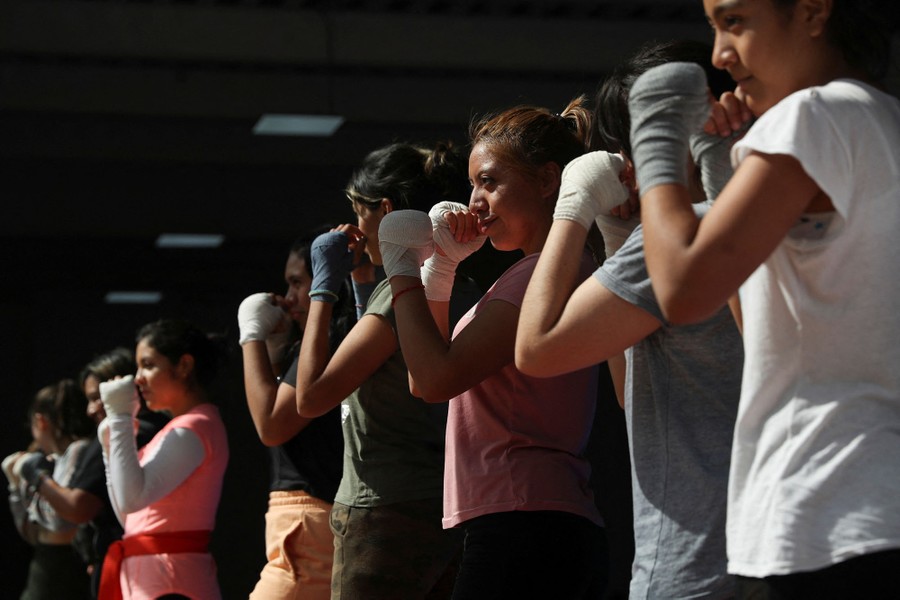About eight women lined up during a class, holding their hands up in defensive poses