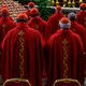 Three rows of cardinals facing away from the camera, wearing red robes and zucchettos