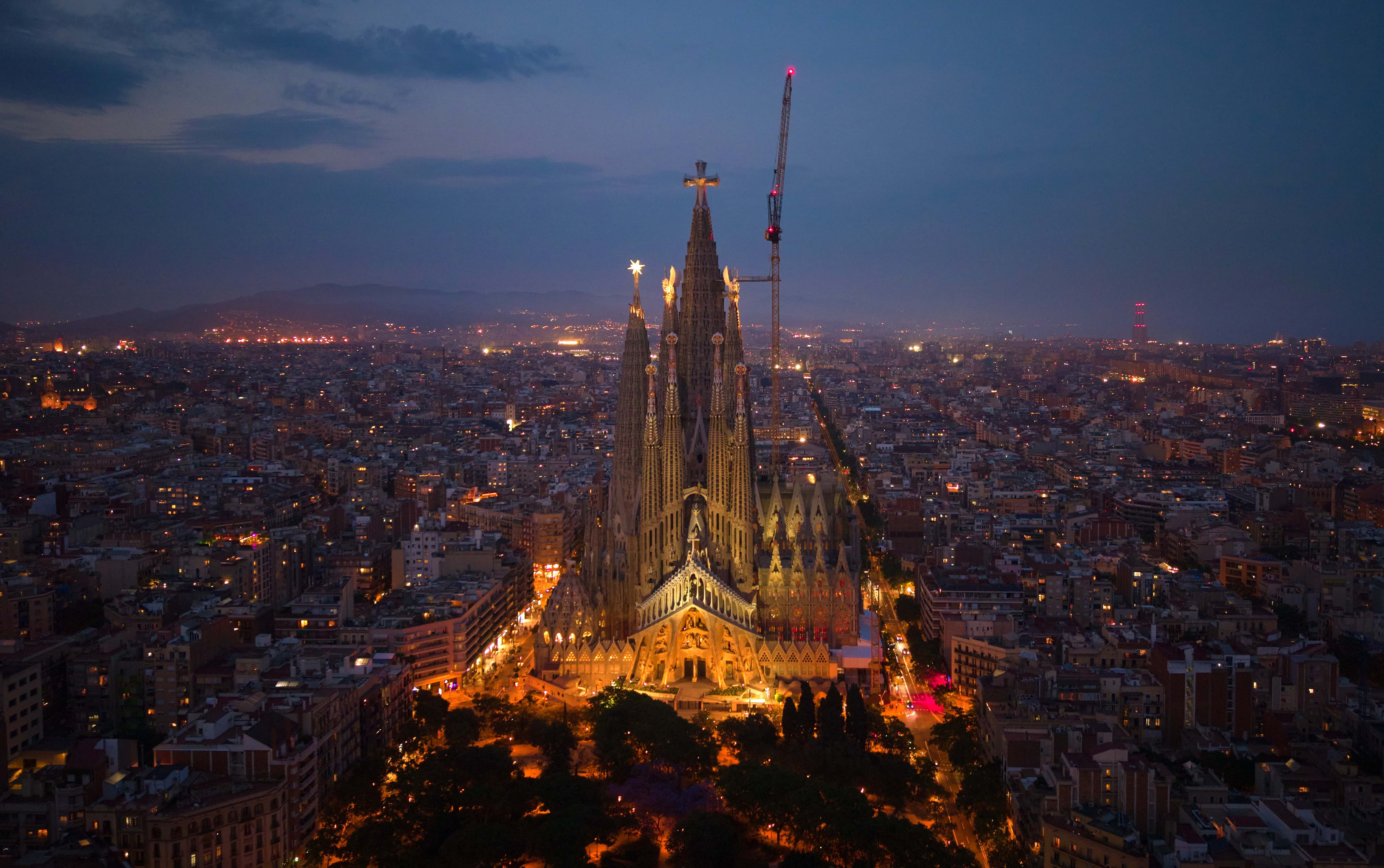A very tall and ornate basilica in Barcelona, illuminated at dusk