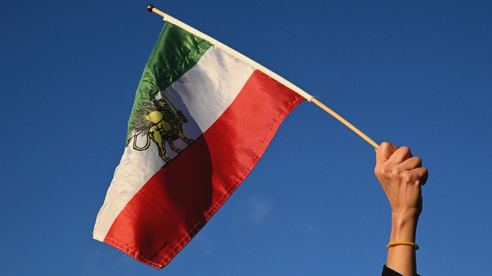 Photograph of a pre-Revolutionary Iranian flag held in the air